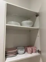 Vajilla en un armario abierto de la cocina del Apartamento Exterior, con platos, cuencos y tazas rosas
